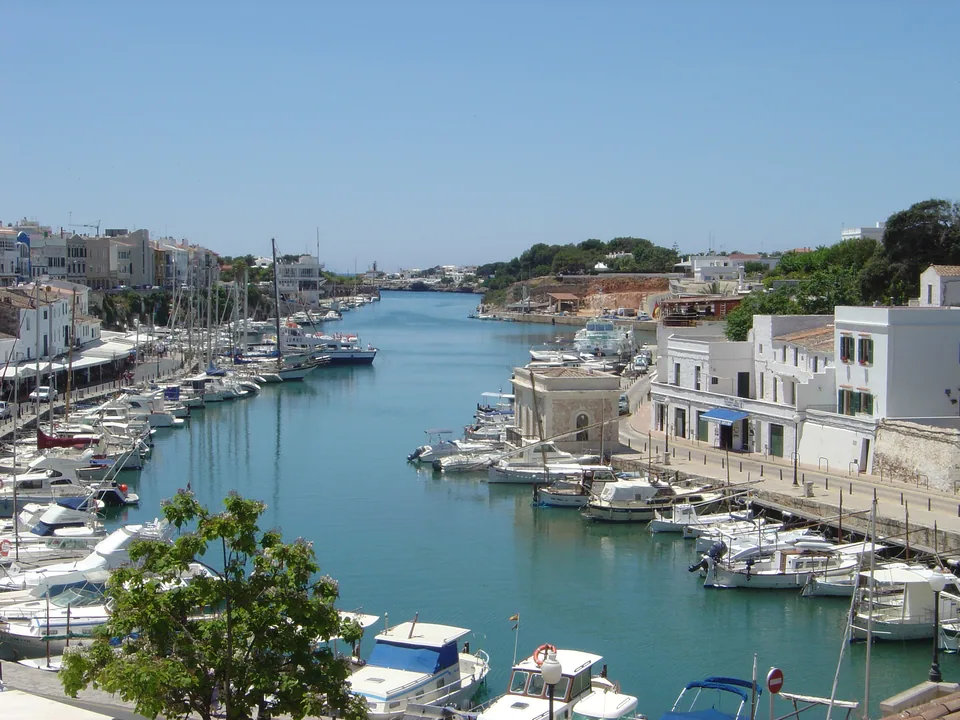 Porto de Ciutadella, com barcos atracados e edifícios junto às duas margens.