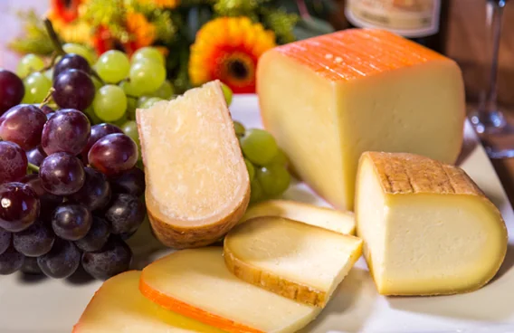 Porções de queijo com uvas, sem embalagem ou marca identificável.