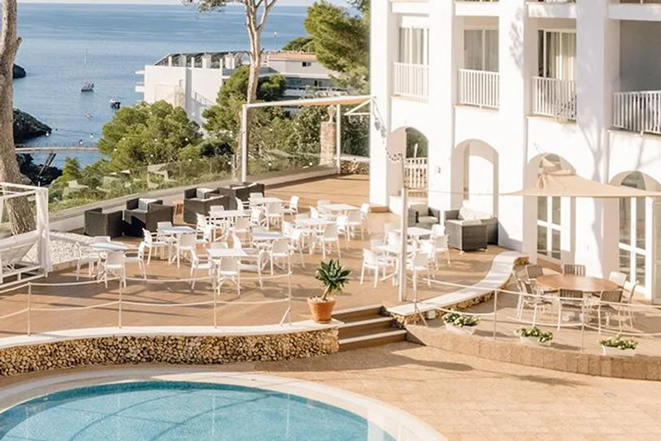 Terraço e parte da piscina do Comitas Floramar, junto à fachada branca.