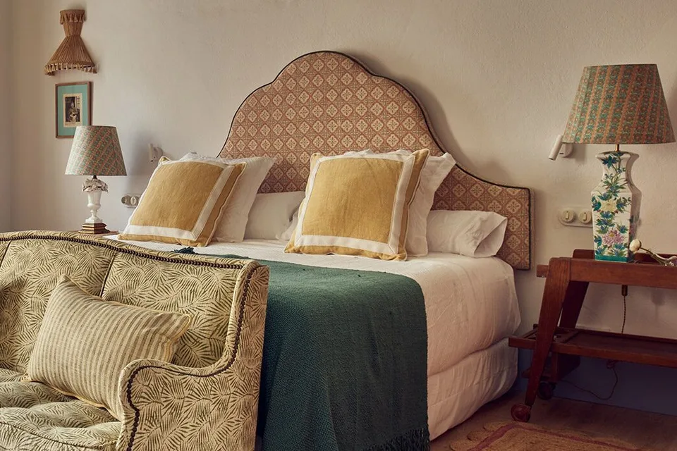Quarto do Cristine Bedfor, com cama, cabeceira estampada e sofá.